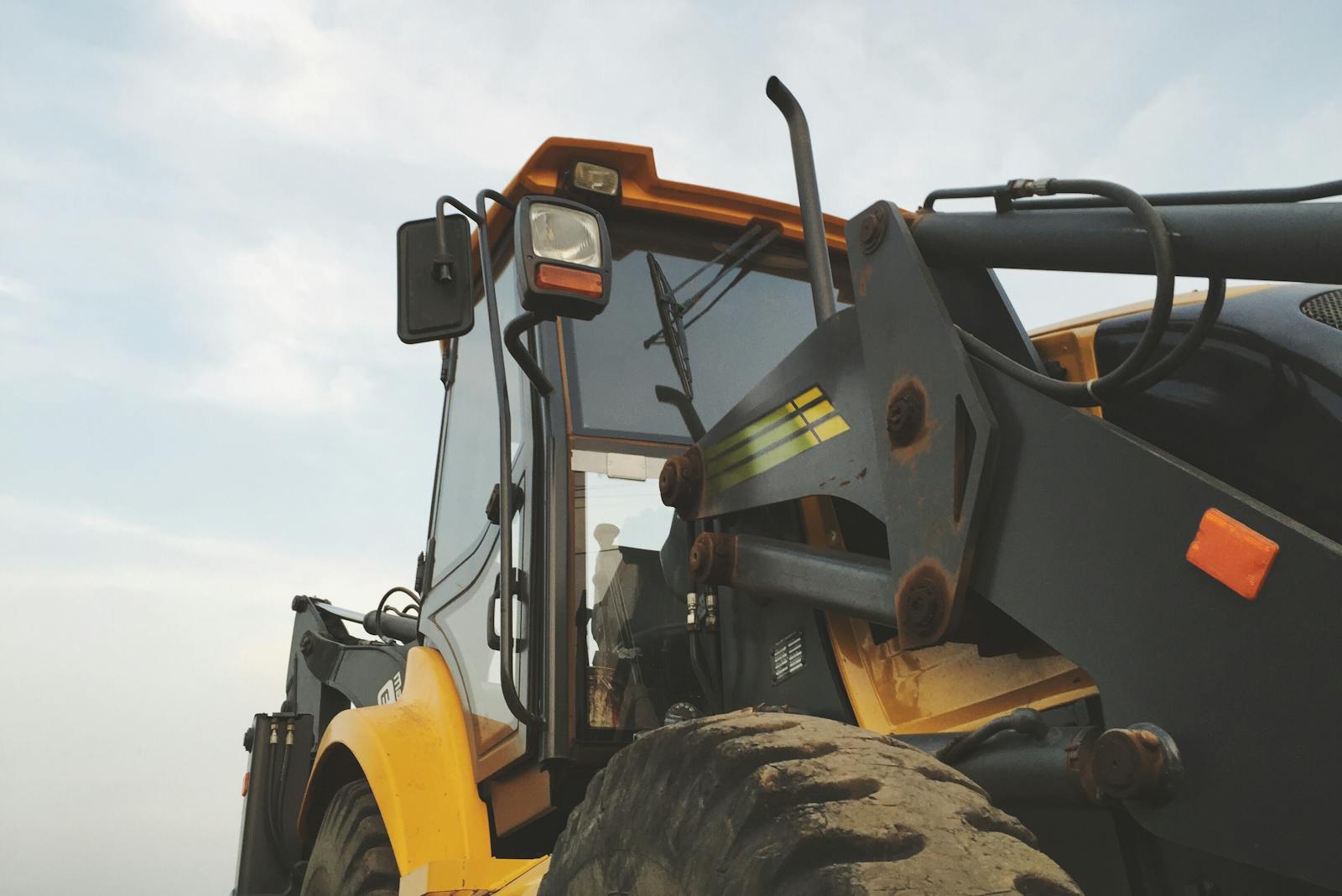 Detailed view of a yellow excavator against a clear sky at a construction site.